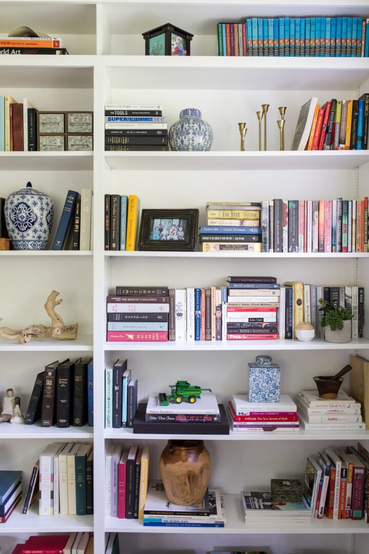 A bookshelf with many books and vases on it