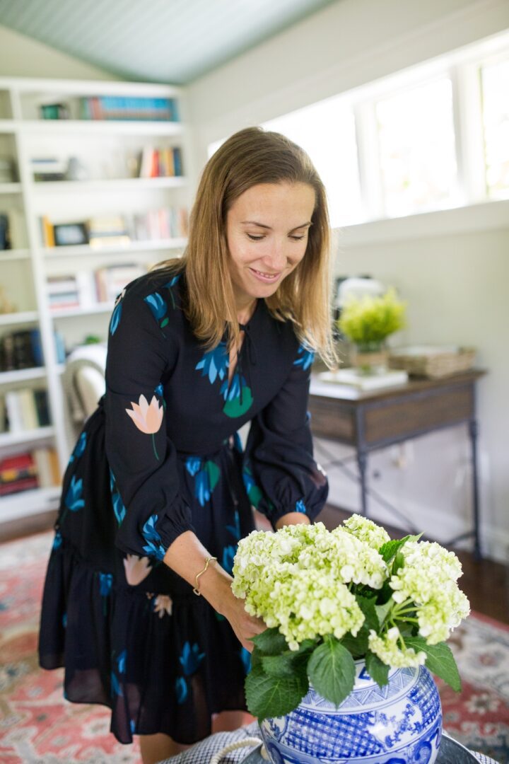 A woman holding a vase of flowers in her hands.