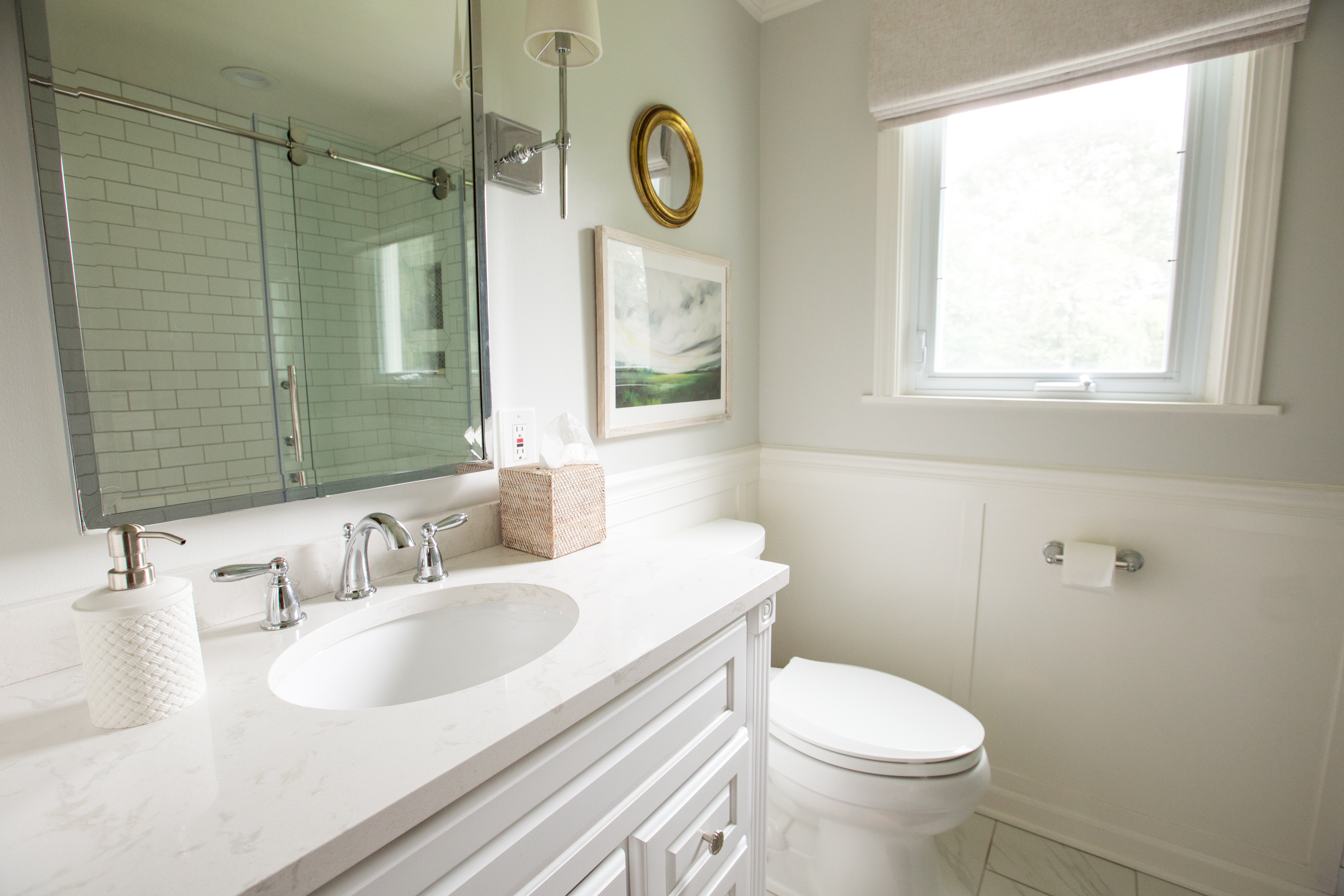 A bathroom with white walls and a large mirror.