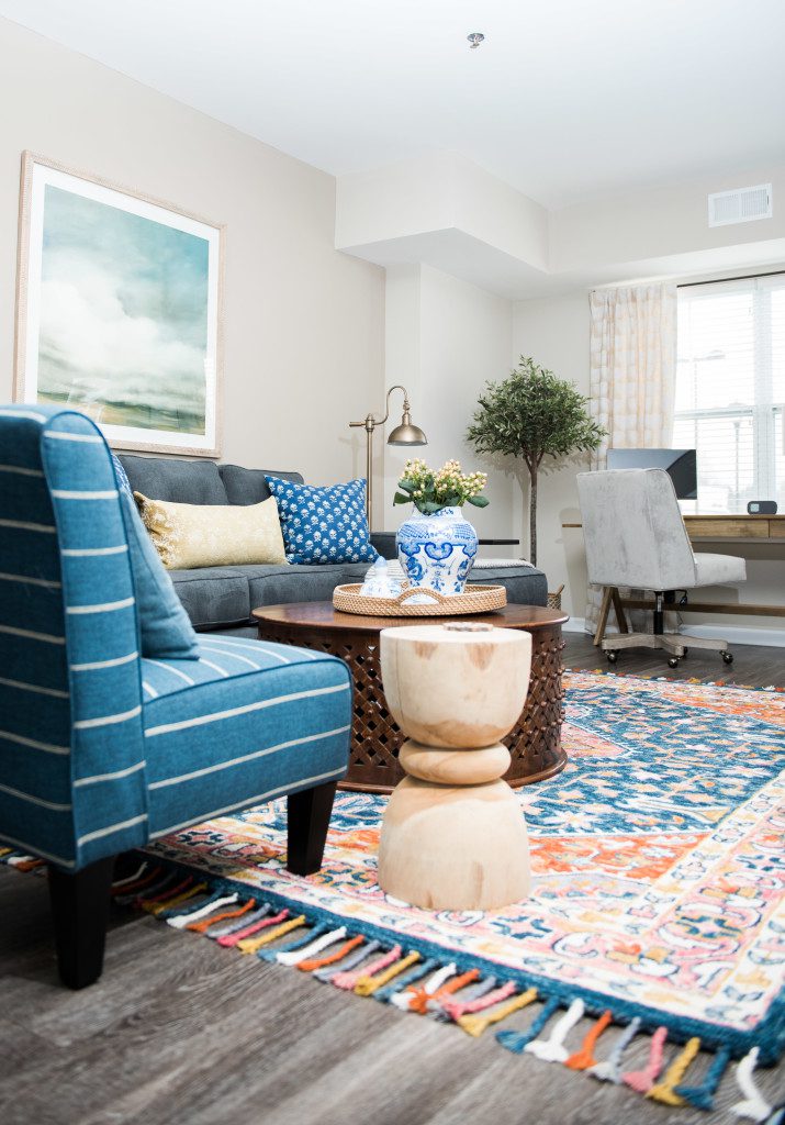 A living room with blue furniture and a colorful rug.