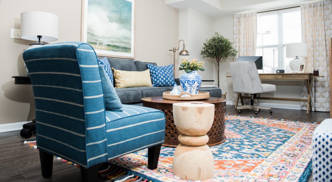 A living room with blue furniture and a colorful rug.