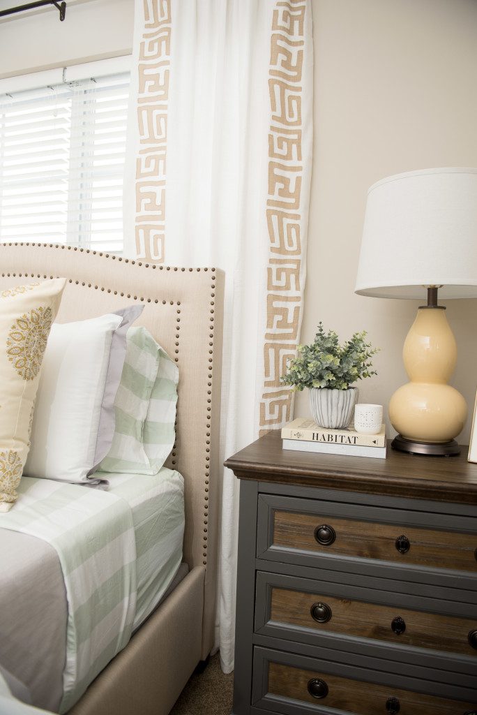 A bedroom with a bed, nightstand and lamp.