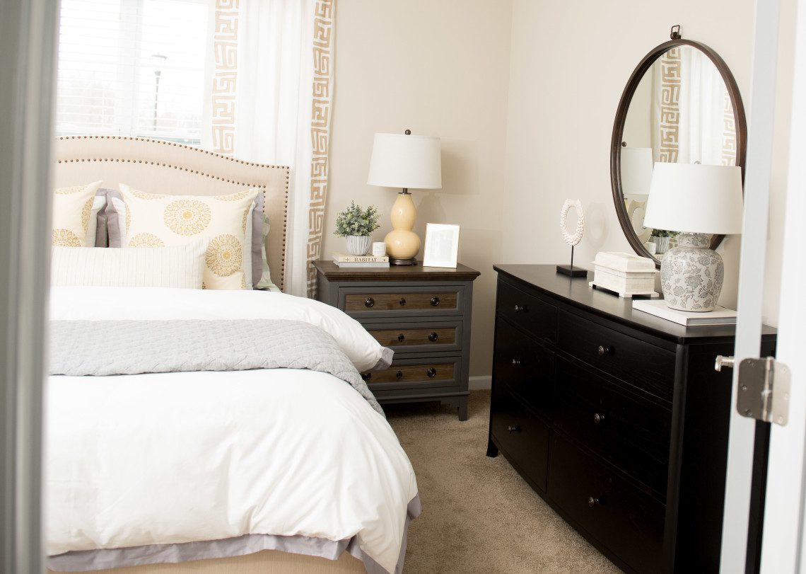 A bedroom with a bed, dresser and mirror.