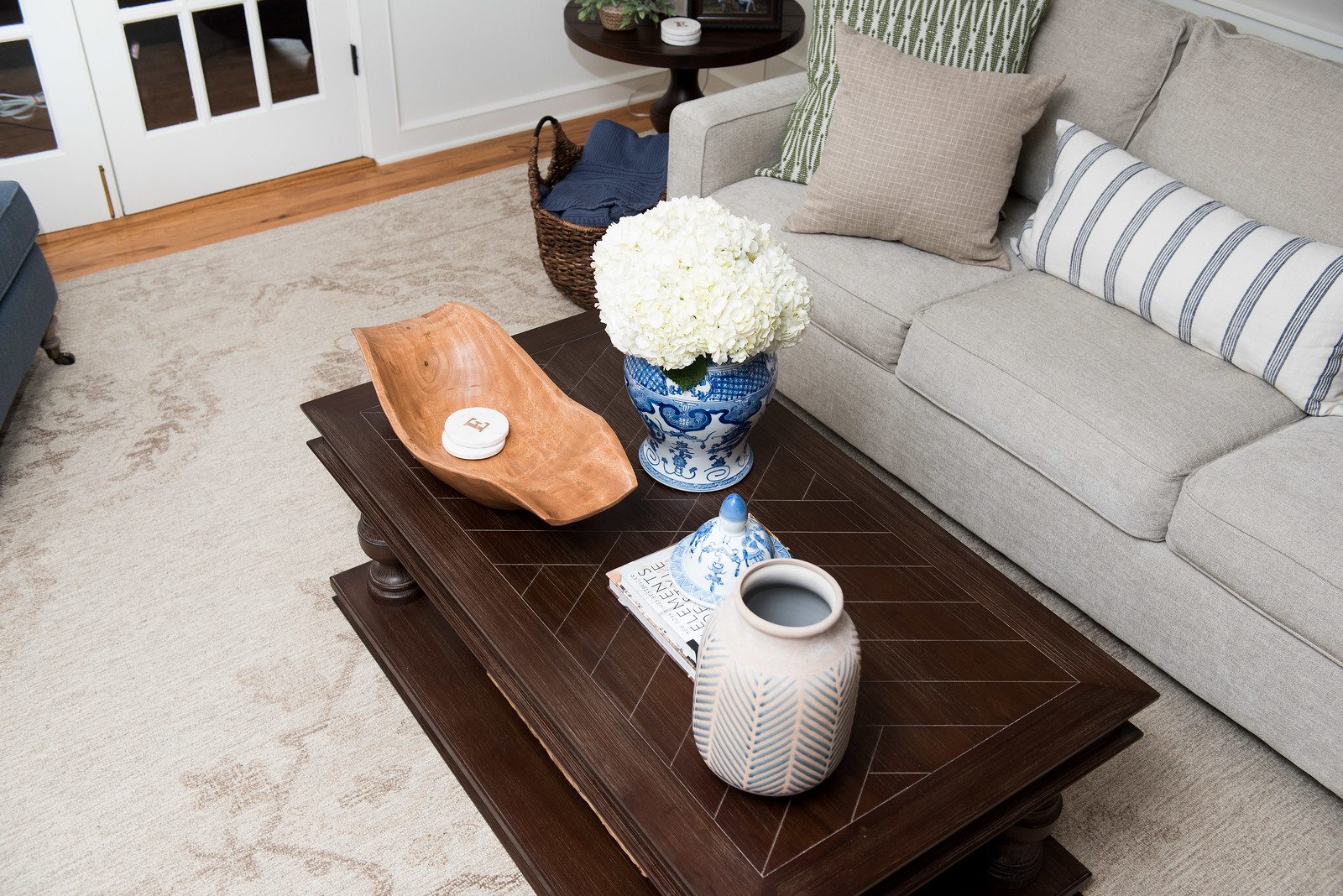 A coffee table with flowers and a vase on it.