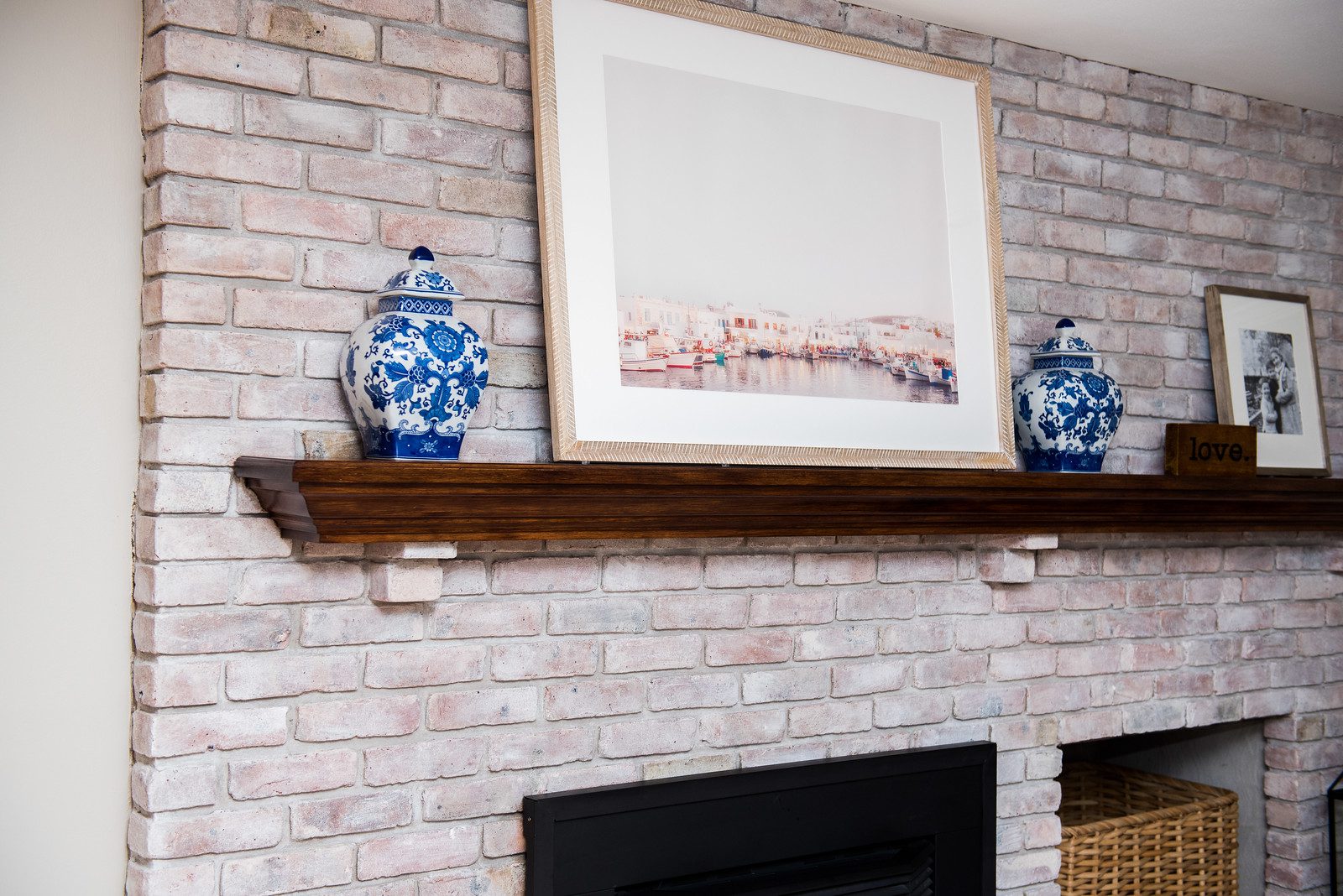A fireplace with two vases on the mantle.